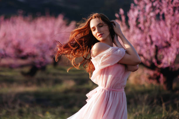 Beautiful young girl under the flowering pink spring tree