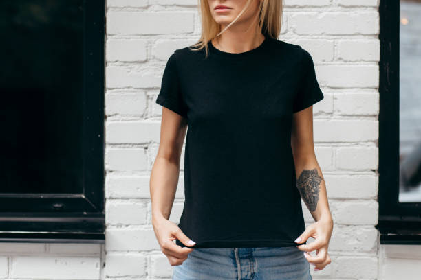 Stylish blonde girl wearing black t-shirt and glasses posing against street , urban clothing style.